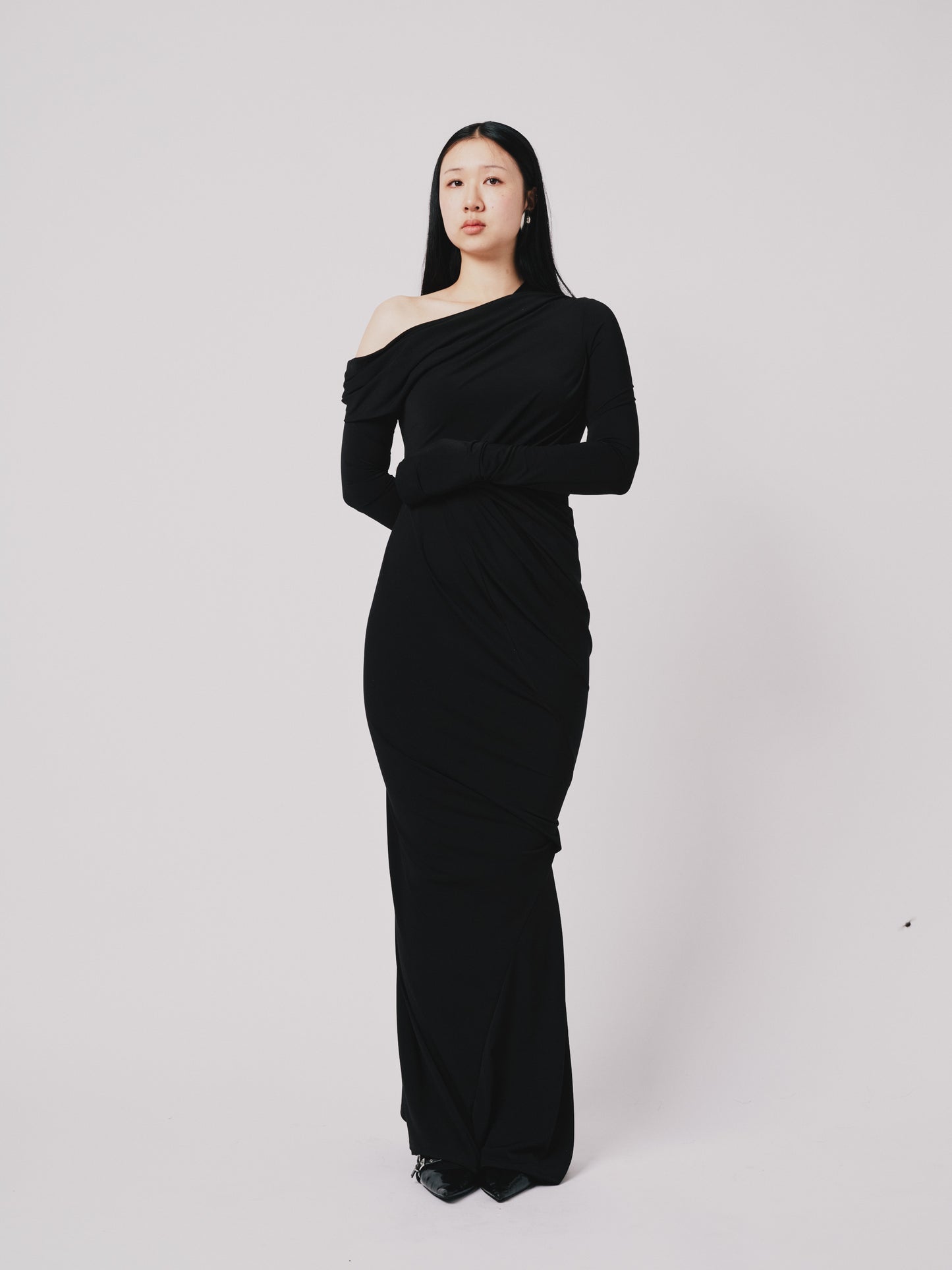 Woman wearing a black off-shoulder gown against a white background front detail view