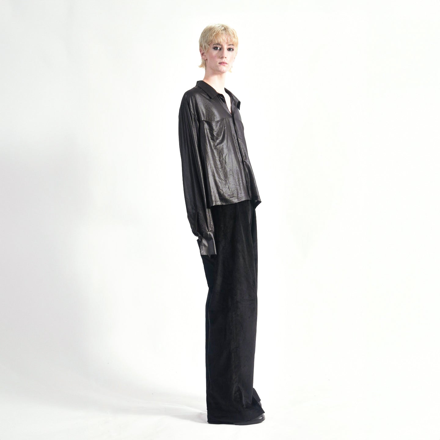 Side view of the Marq Shirt in Liquid Black highlighting the sleeve drape detail and button closure and inseam front pockets.