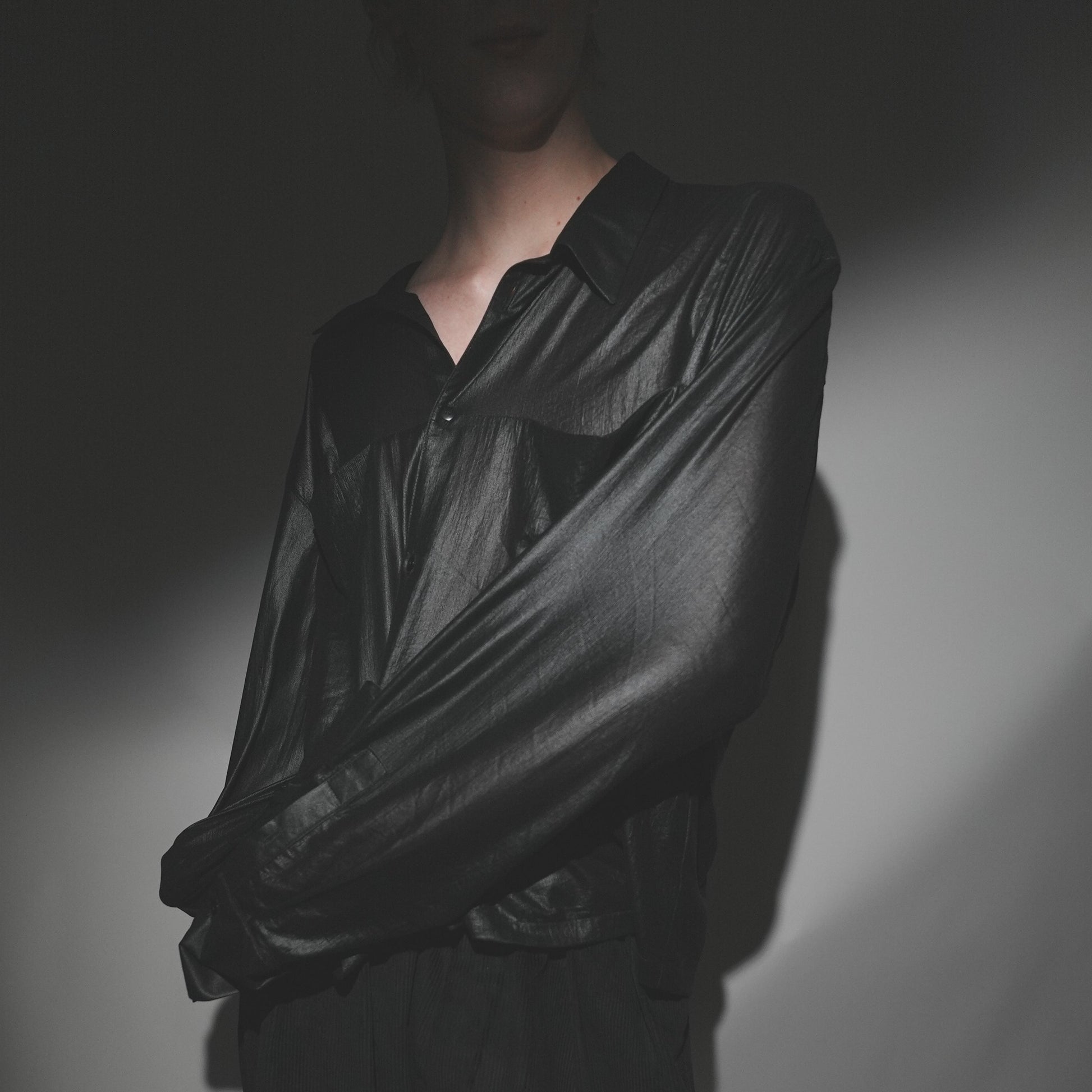 Close-up shot of the Marq Shirt in Liquid Black detailing the drape, inseam pocket detail, and button closure and sleeve and cuff detail.