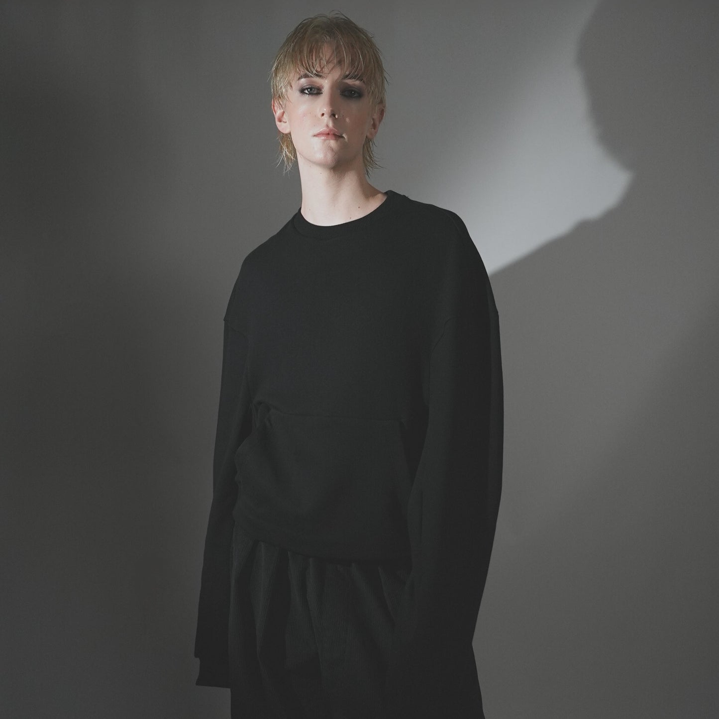 Close-up shot of the Hoffman Crewneck in Black detailing the fit, front pouch pocket detail and long sleeve.