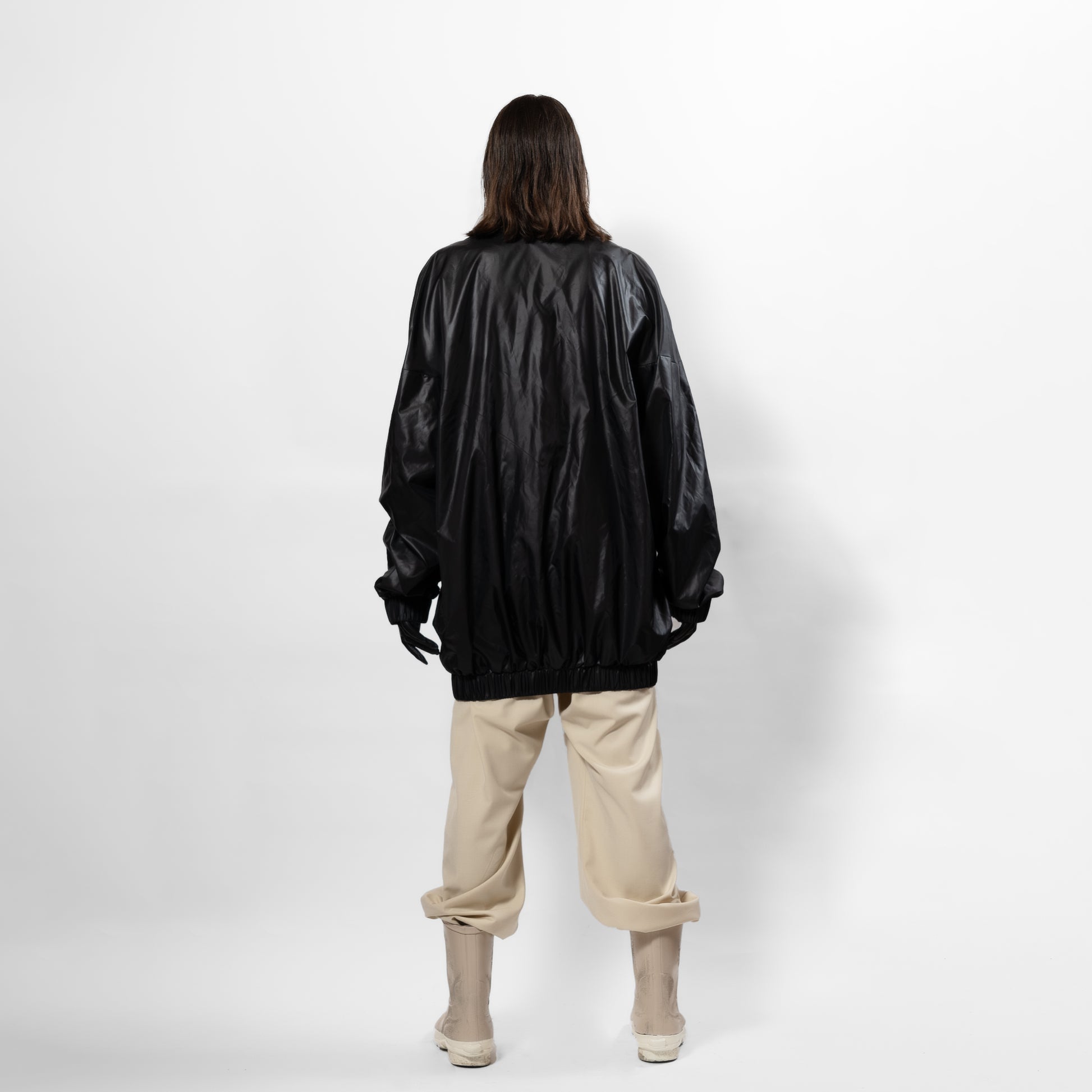 Black 90's inspired windbreaker Jacket with slight Sheen. Front zip, elasticated bottom hem and cuff. long front zip. one size fits all. Back full view.