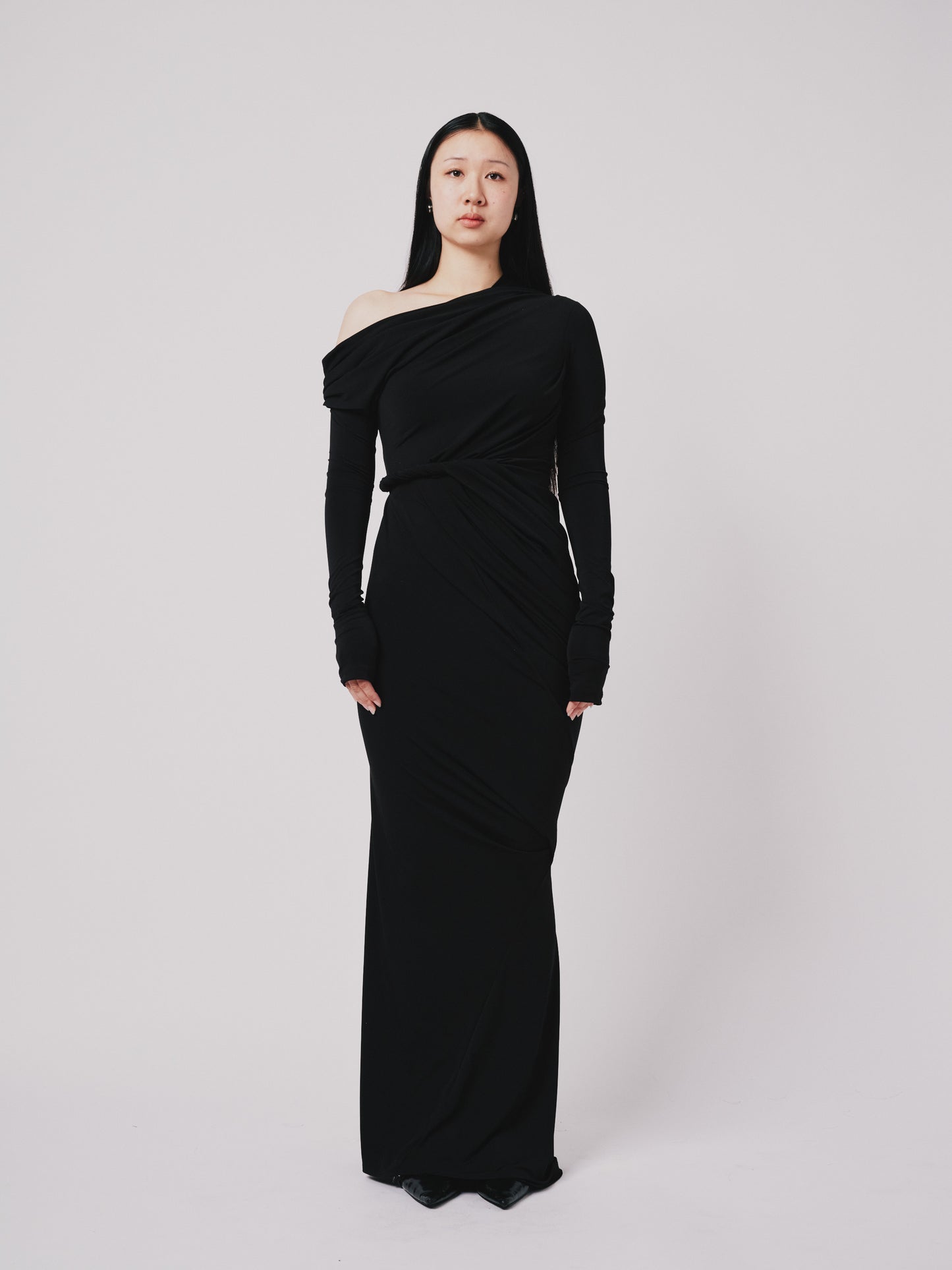 Woman wearing a black one-shoulder dress against a white background front view