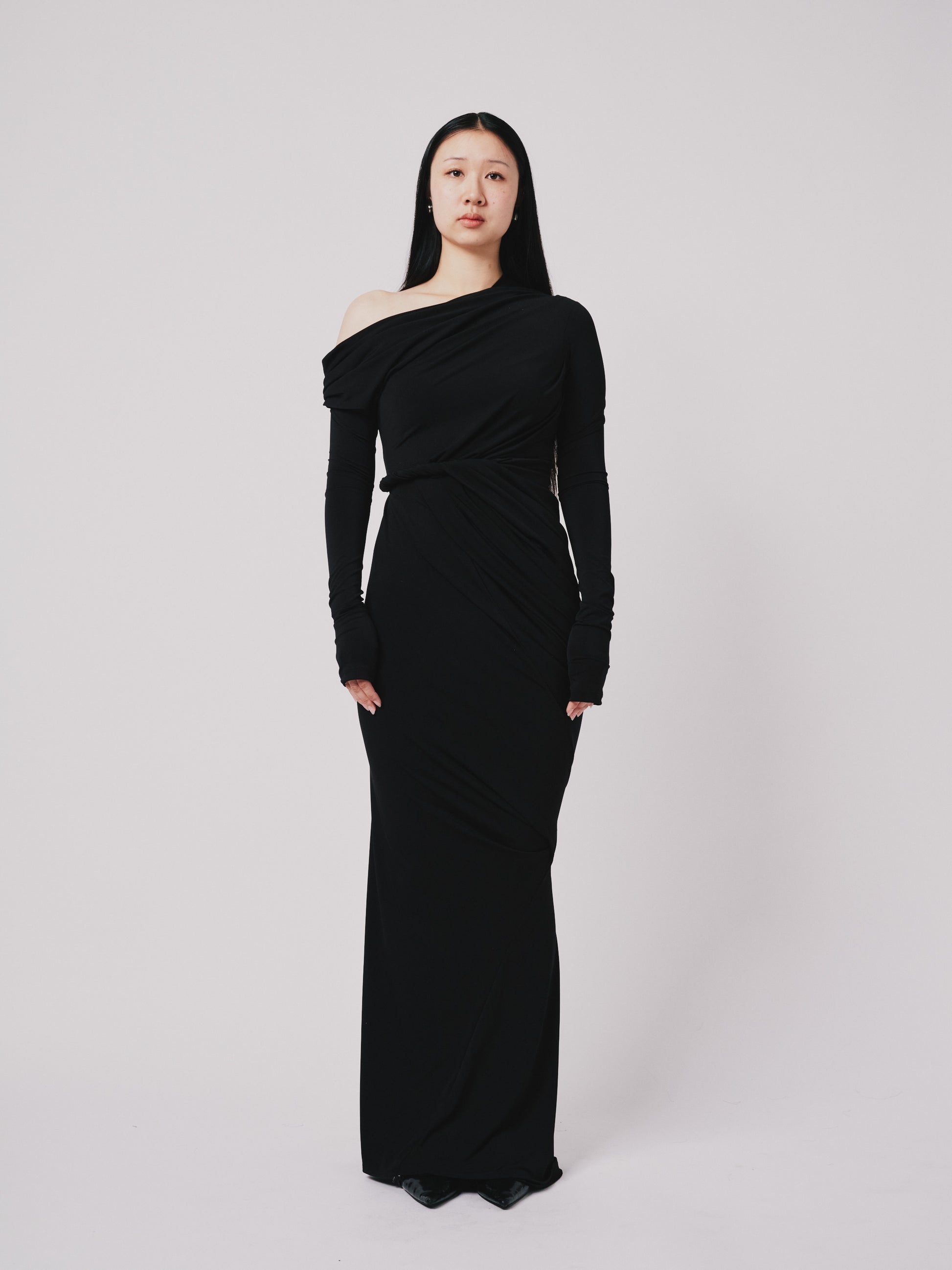 Woman wearing a black one-shoulder dress against a white background front view