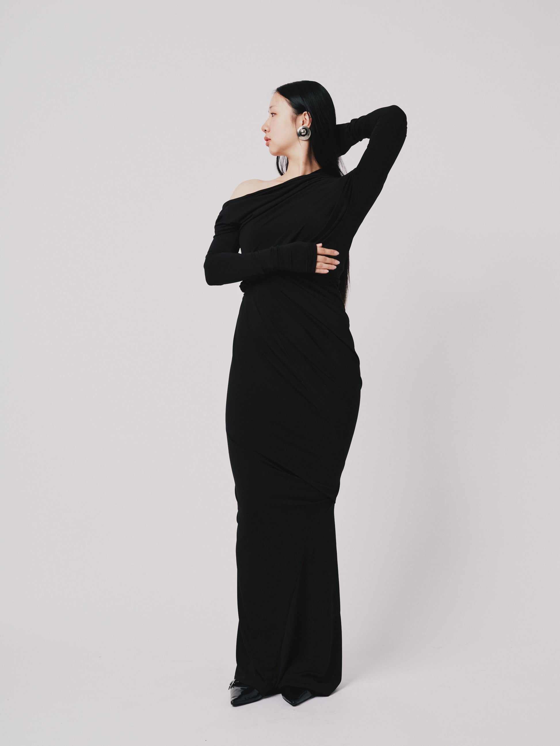 Woman wearing a black off-shoulder dress against a white background posing