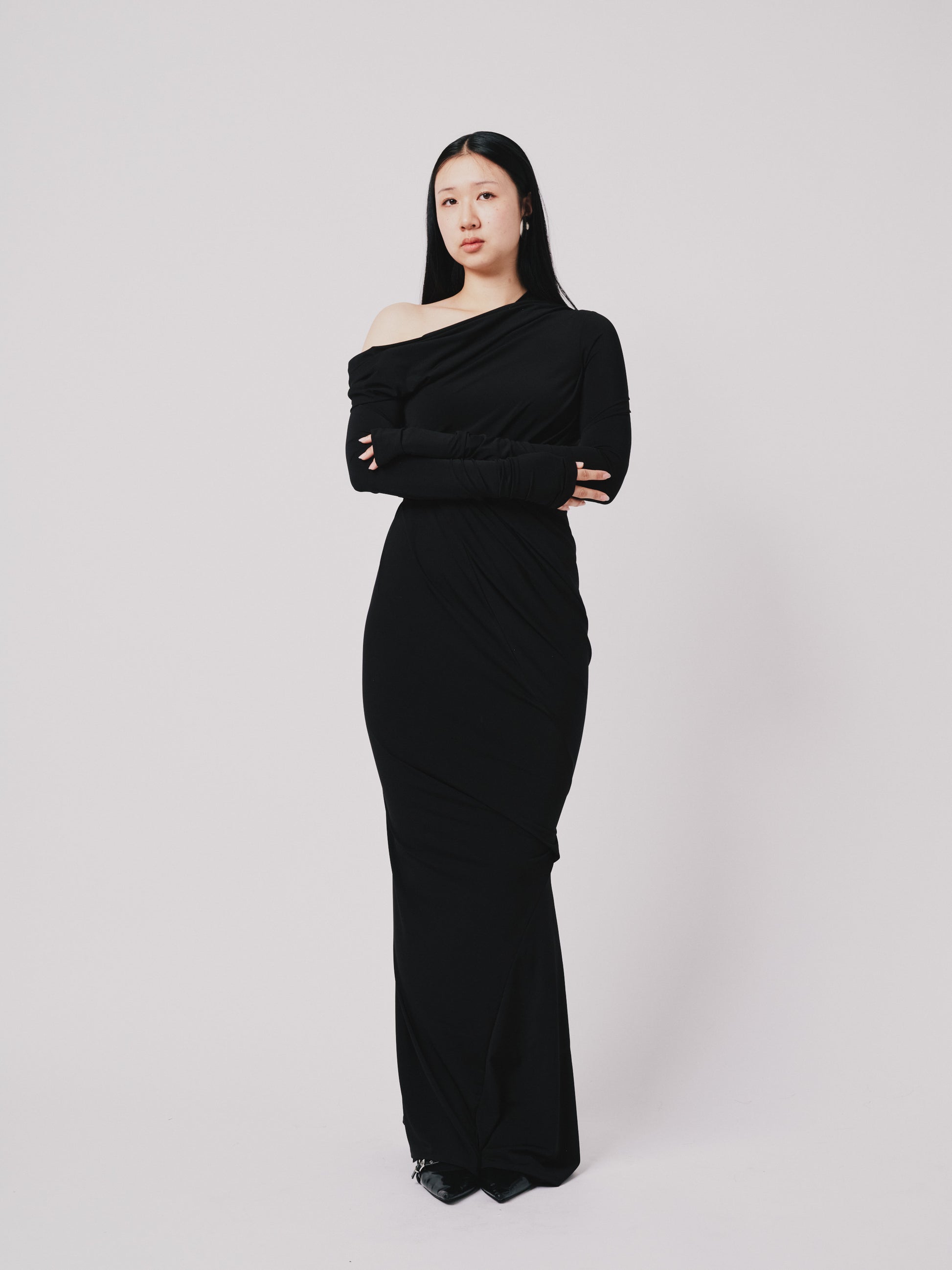 Woman wearing a black one-shoulder dress against a white background