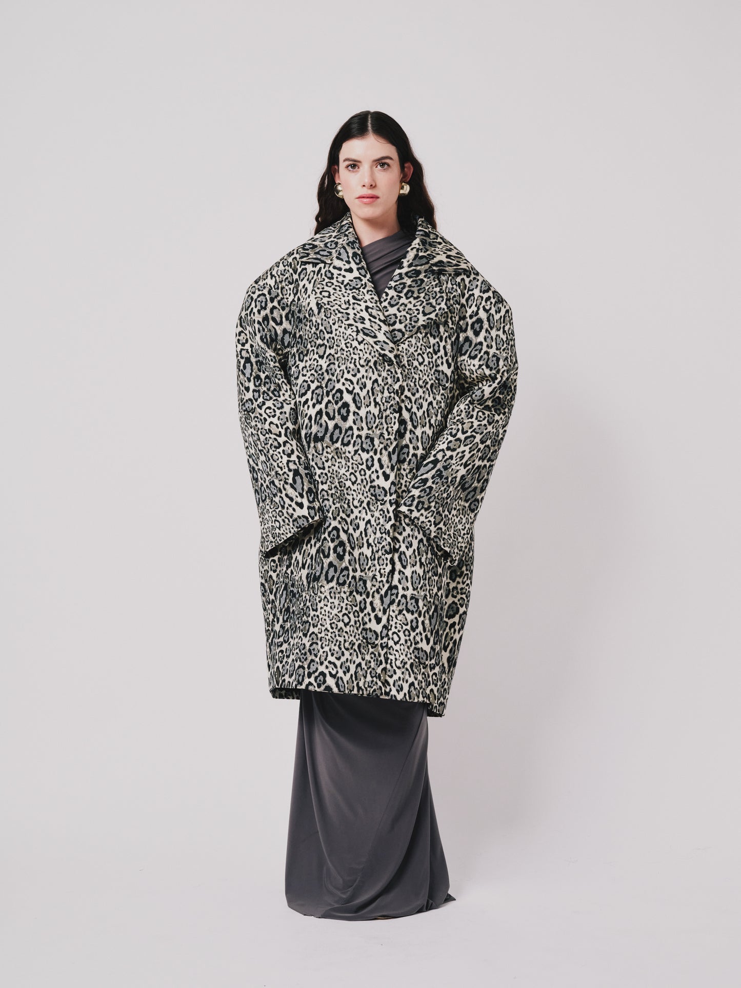 Person wearing a leopard print coat on a plain background