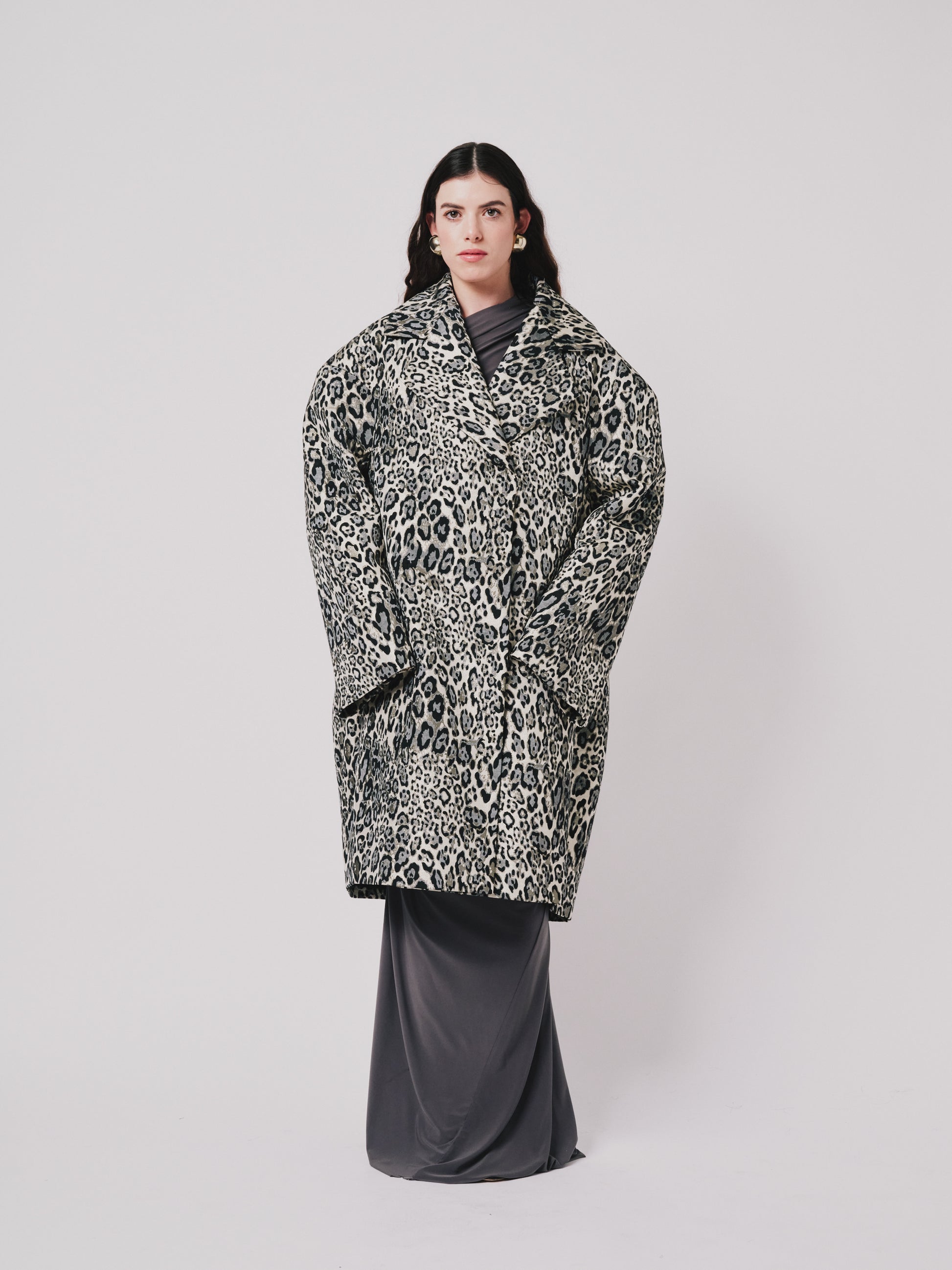 Person wearing a leopard print coat on a plain background