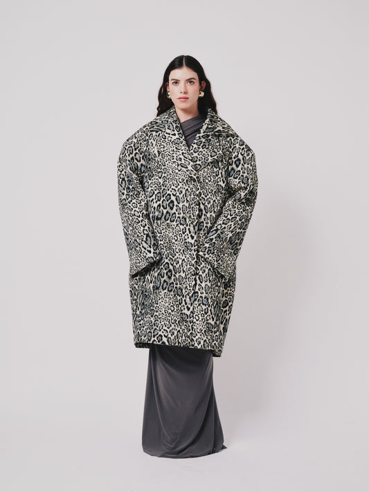 Person wearing a leopard print coat on a plain background