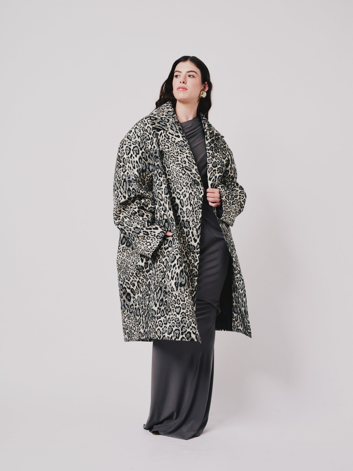 Person wearing a leopard print coat on a plain background left side view 