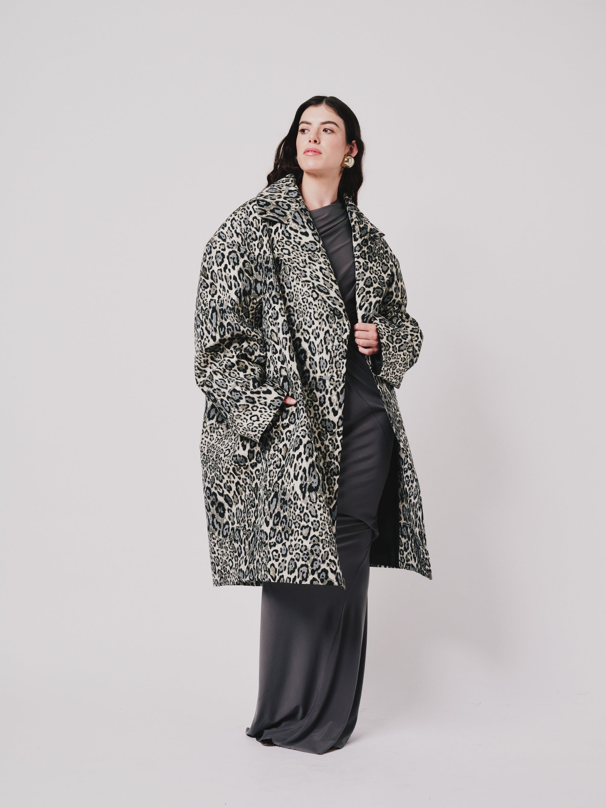 Person wearing a leopard print coat on a plain background left side view 