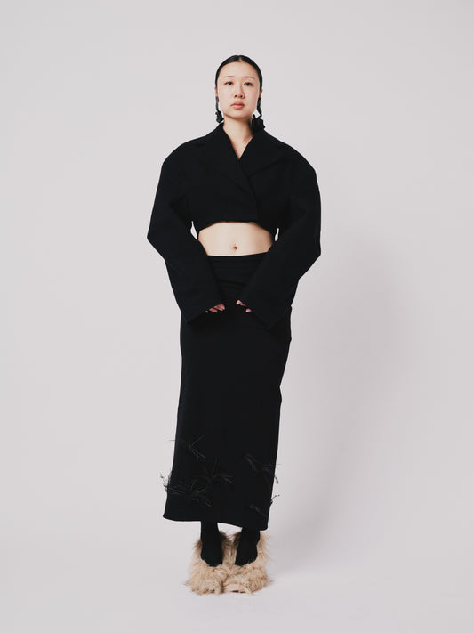 Person wearing a black cropped Hoffman jacket with a white background front view