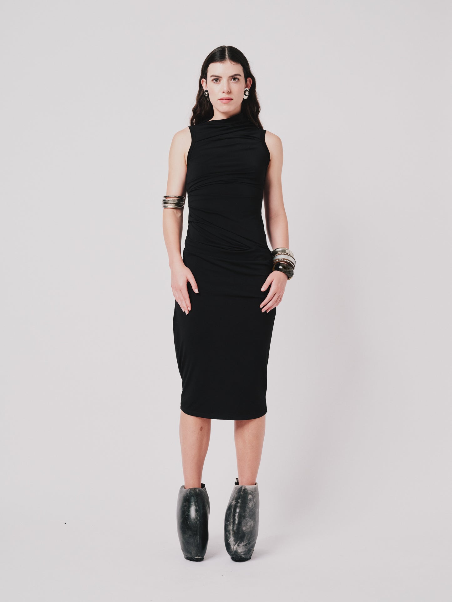 Woman wearing a black Paloma  dress with shoes on a light grey background front view