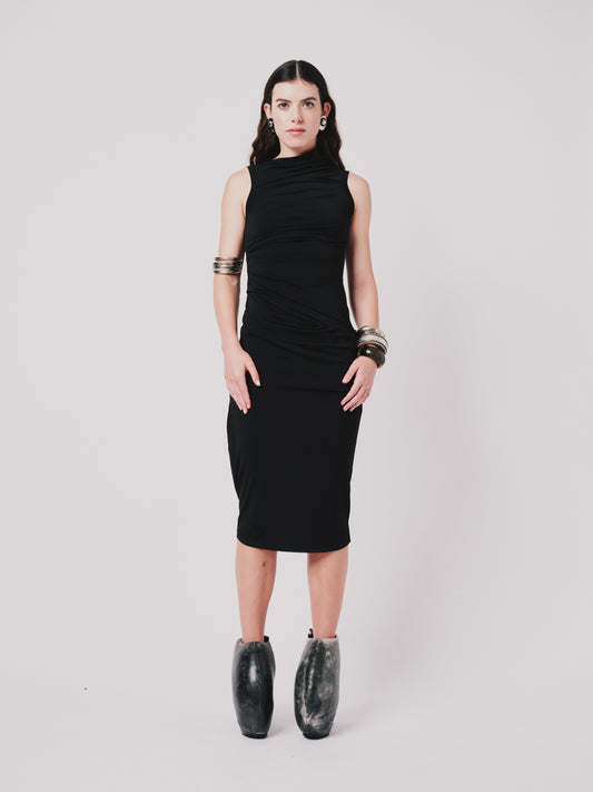 Woman wearing a black Paloma  dress with shoes on a light grey background front view