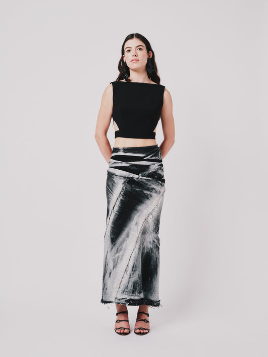Woman wearing a structured drape skirt in distressed black denim on a plain background. Front view