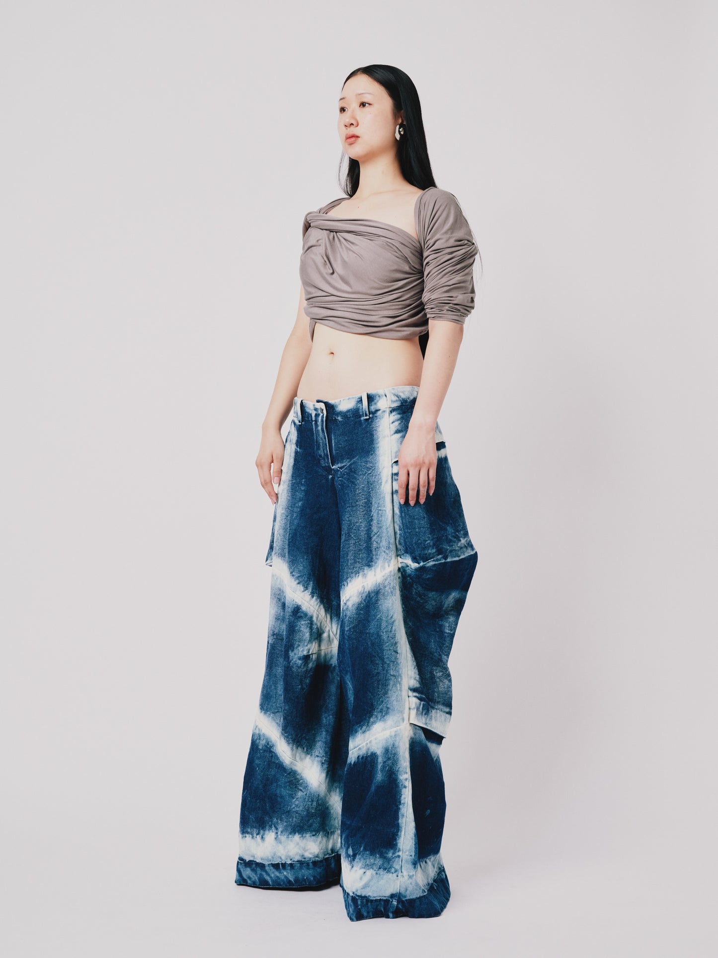 Person wearing distressed cargo pant in blue denim on white background. Side view