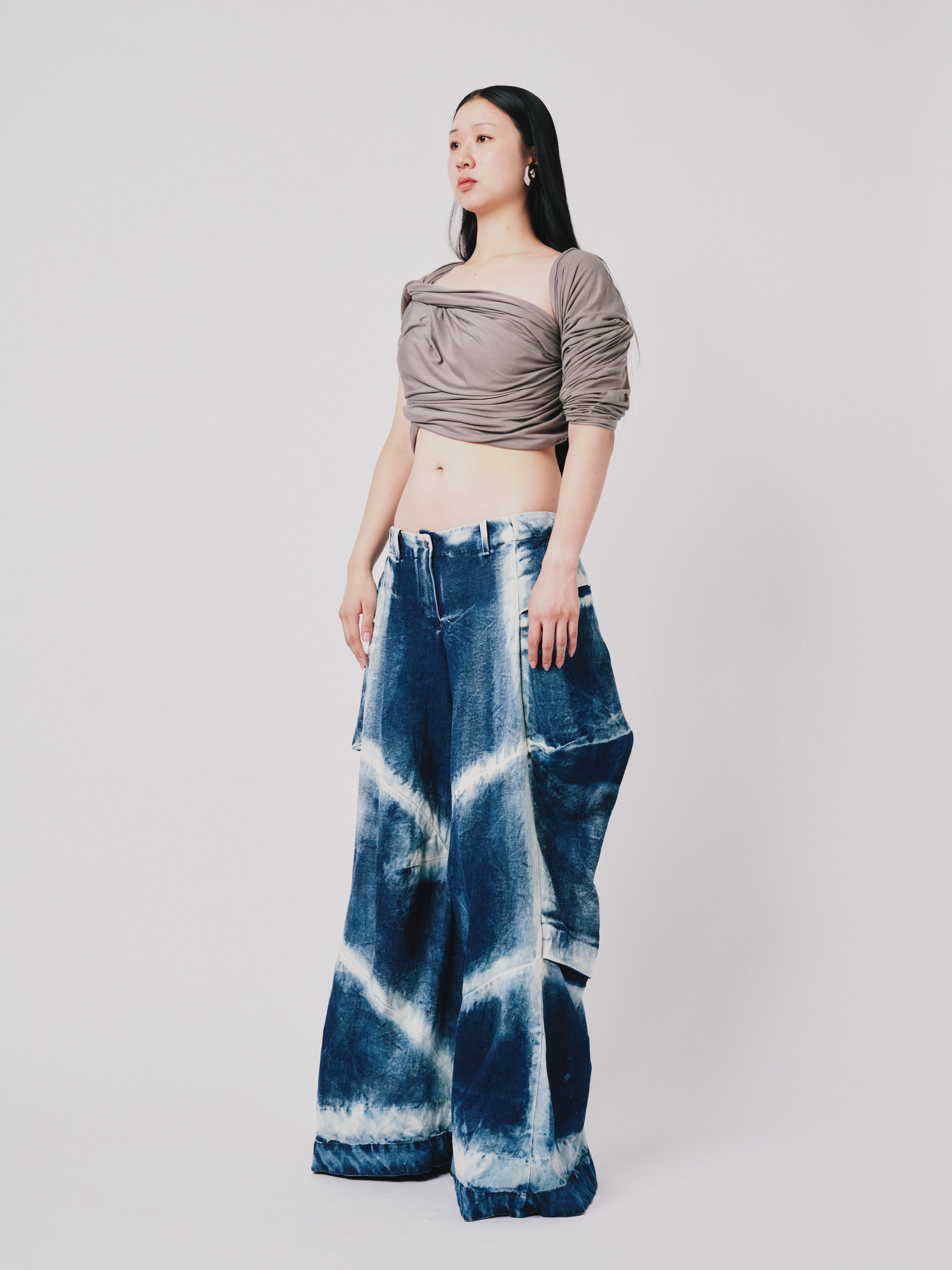 Person wearing distressed cargo pant in blue denim on white background. Side view