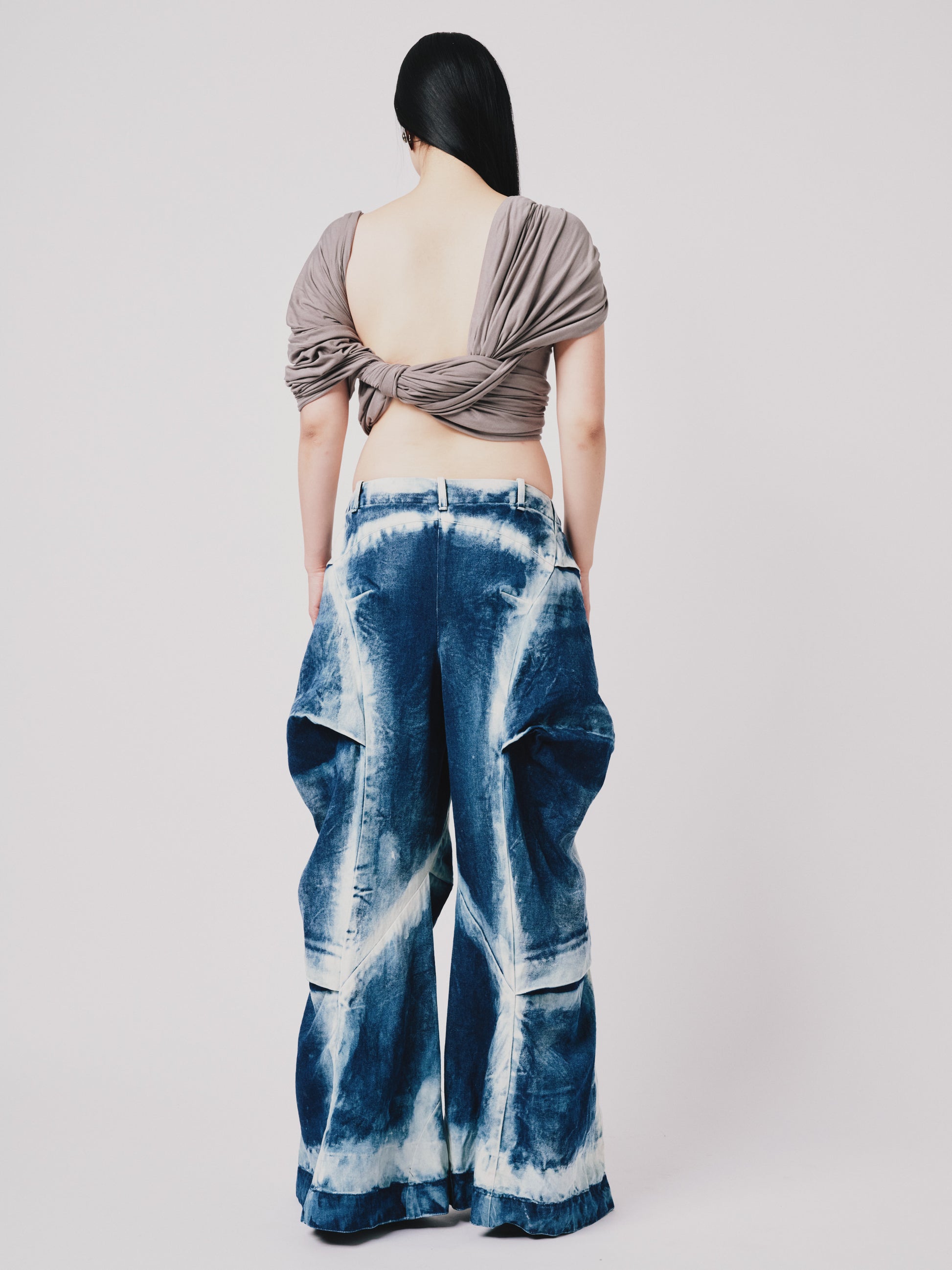 Person wearing distressed cargo pant in blue denim on white background. Back view