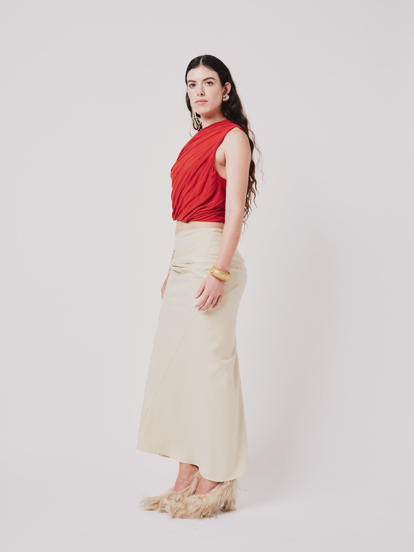Woman wearing a top and structured draped skirt in pear sorbet. Side view