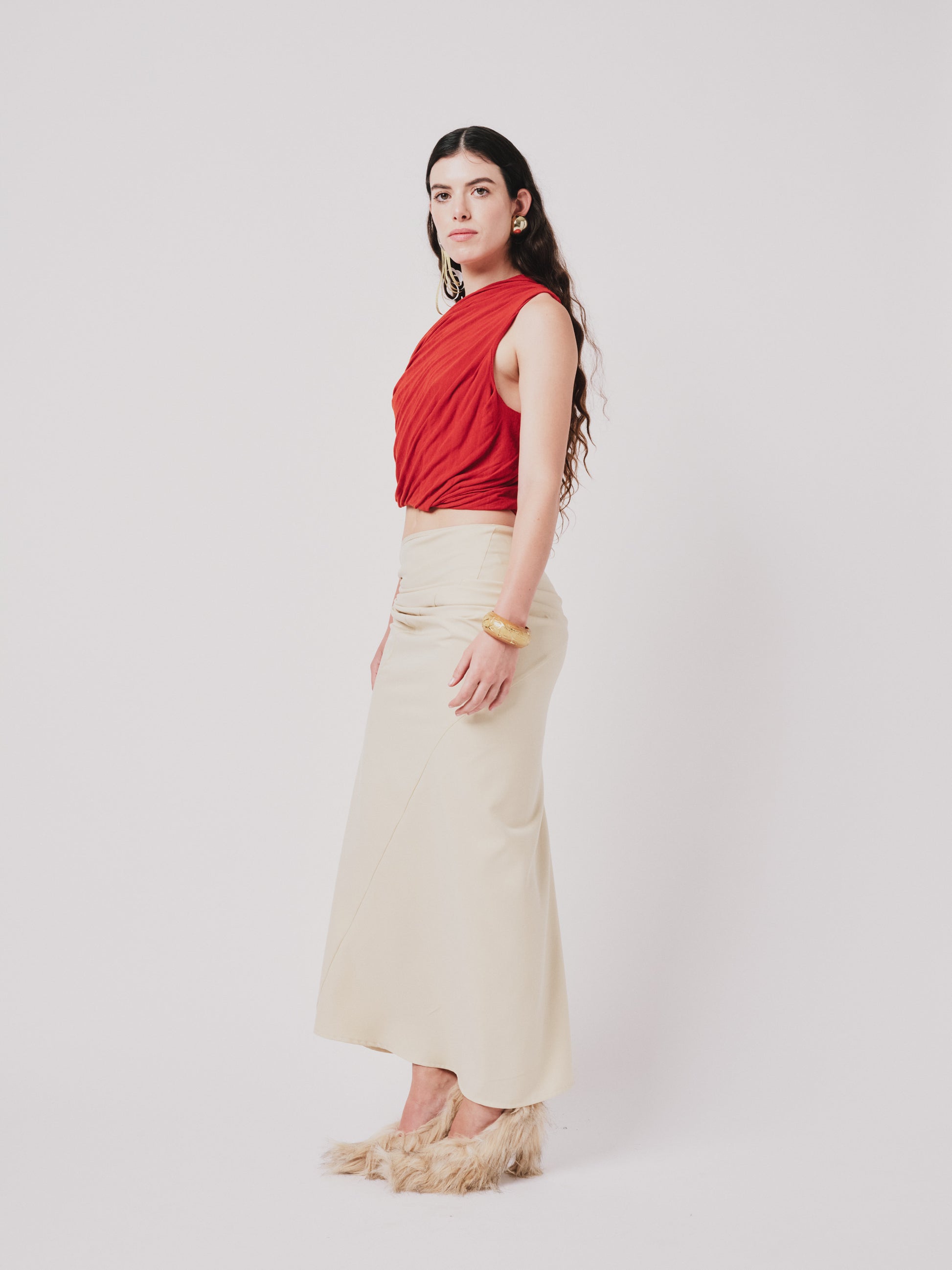 Woman wearing a top and structured draped skirt in pear sorbet. Side view
