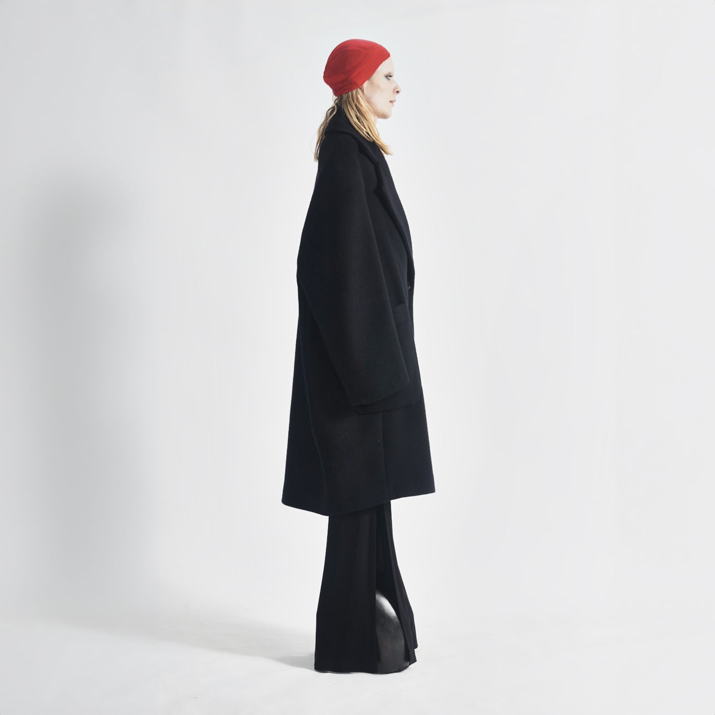 Side view of the black Hoffman Coat showing the off-the-shoulder fit and bold structured silhouette.