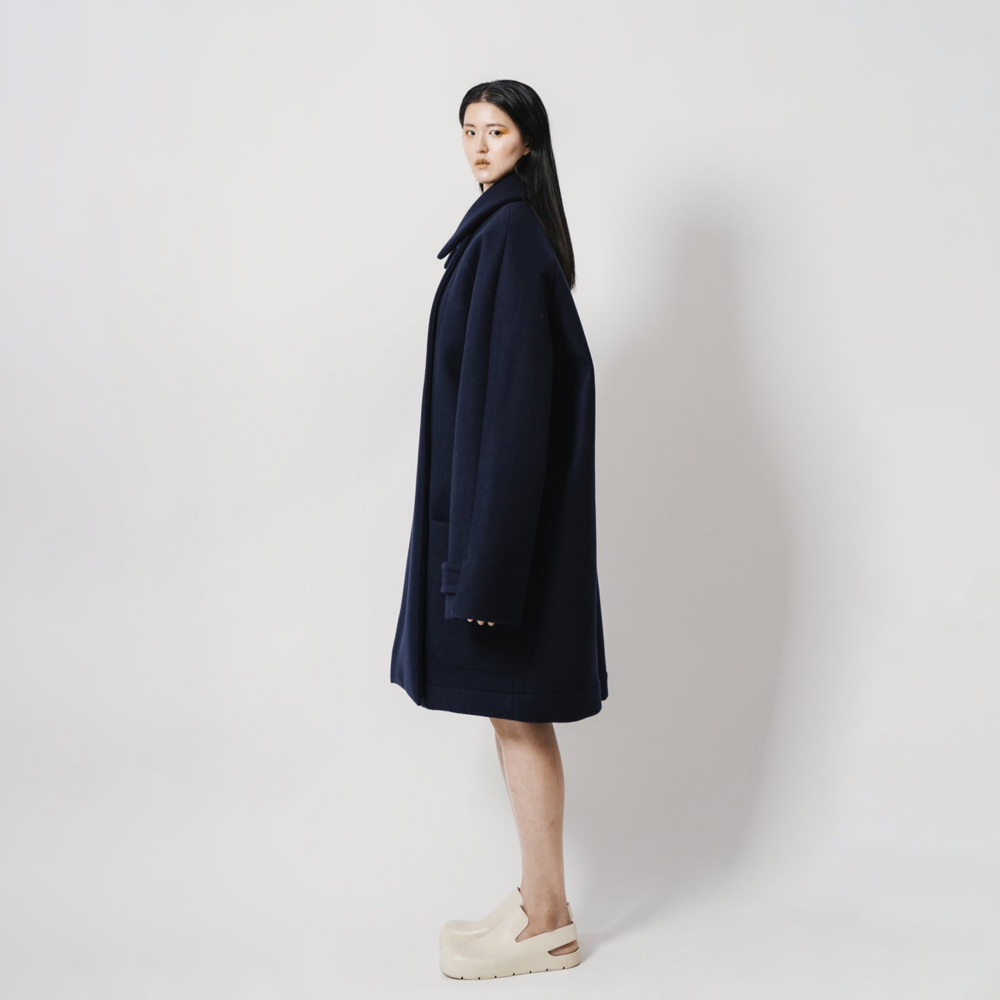 Oversize Navy Blue Neoprene Coat with oversize front pockets. Oversize Fit. Side view.